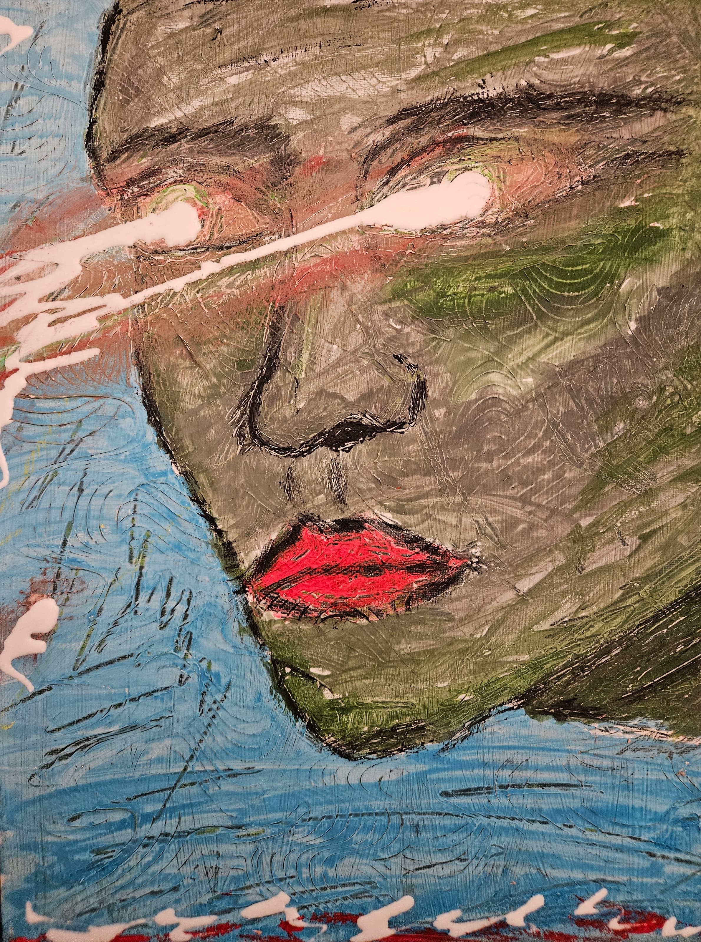 Painted face in muted green and brown against a blue field, with pale paint crossing the eyes and bright red lips.